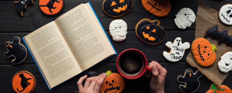 A book on a table surrounded by Halloween cookies.