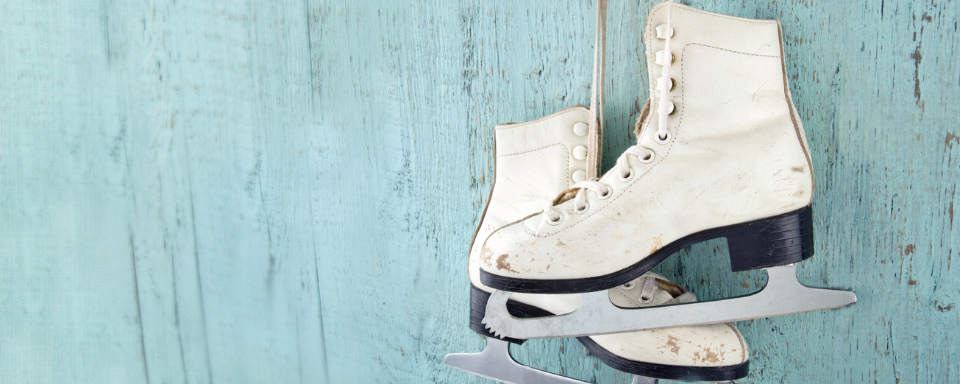 A pair of figure skates dangle on a blue background.