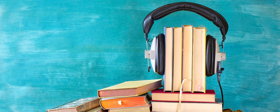 A short row of books with headphones clamped around them.